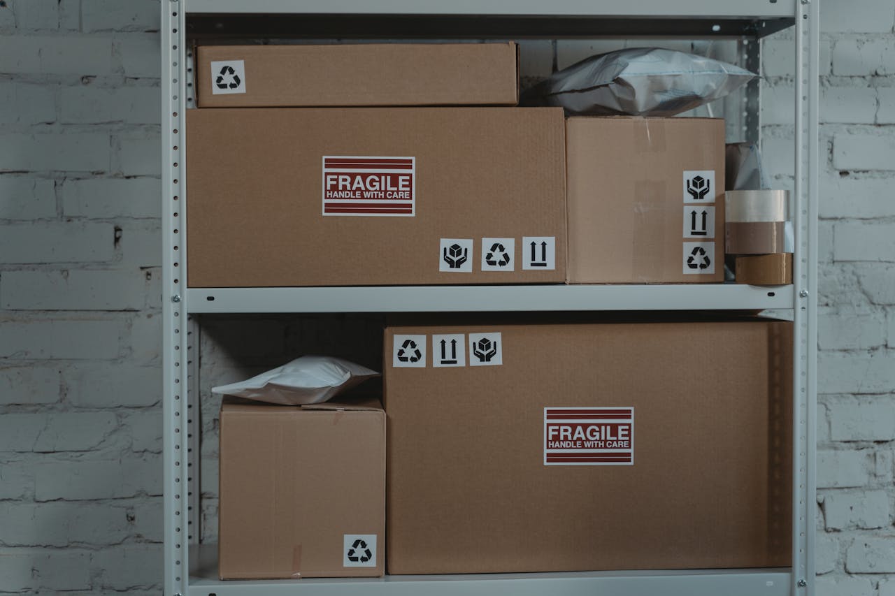 Services-03 Cardboard boxes labeled 'Fragile' stacked on metal shelving in a storage room.